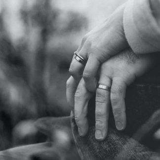 two persons holding hands, with wedding rings